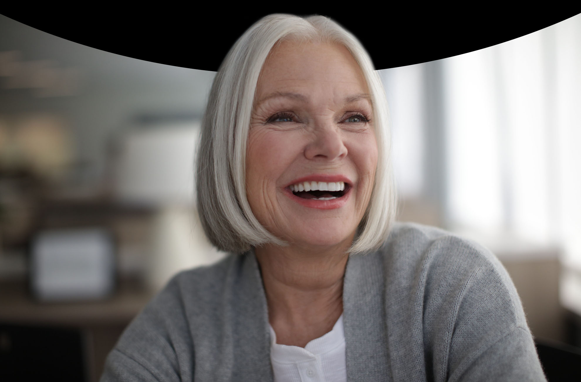 Woman with grey hair and fair skin smiling jovially